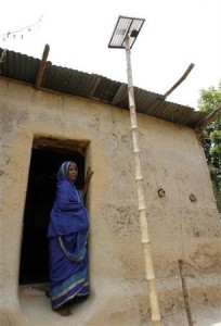 A woman stands in the doorway of her mud house next to a solar system panel near Patulia village in the Gazipur district north of capital Dhaka in this May 5, 2007 photo.